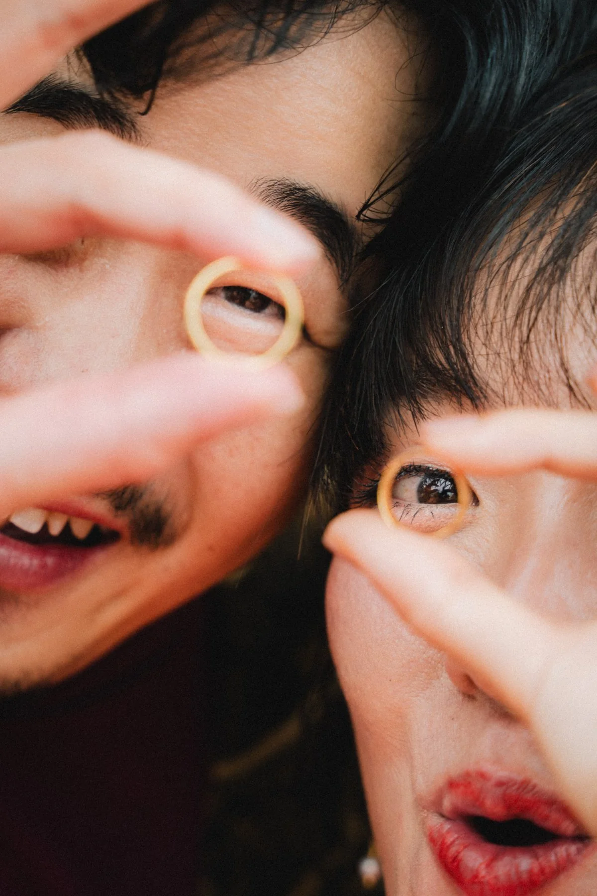 Andrew and Pheobe playfully holding their rings in front of their eyes