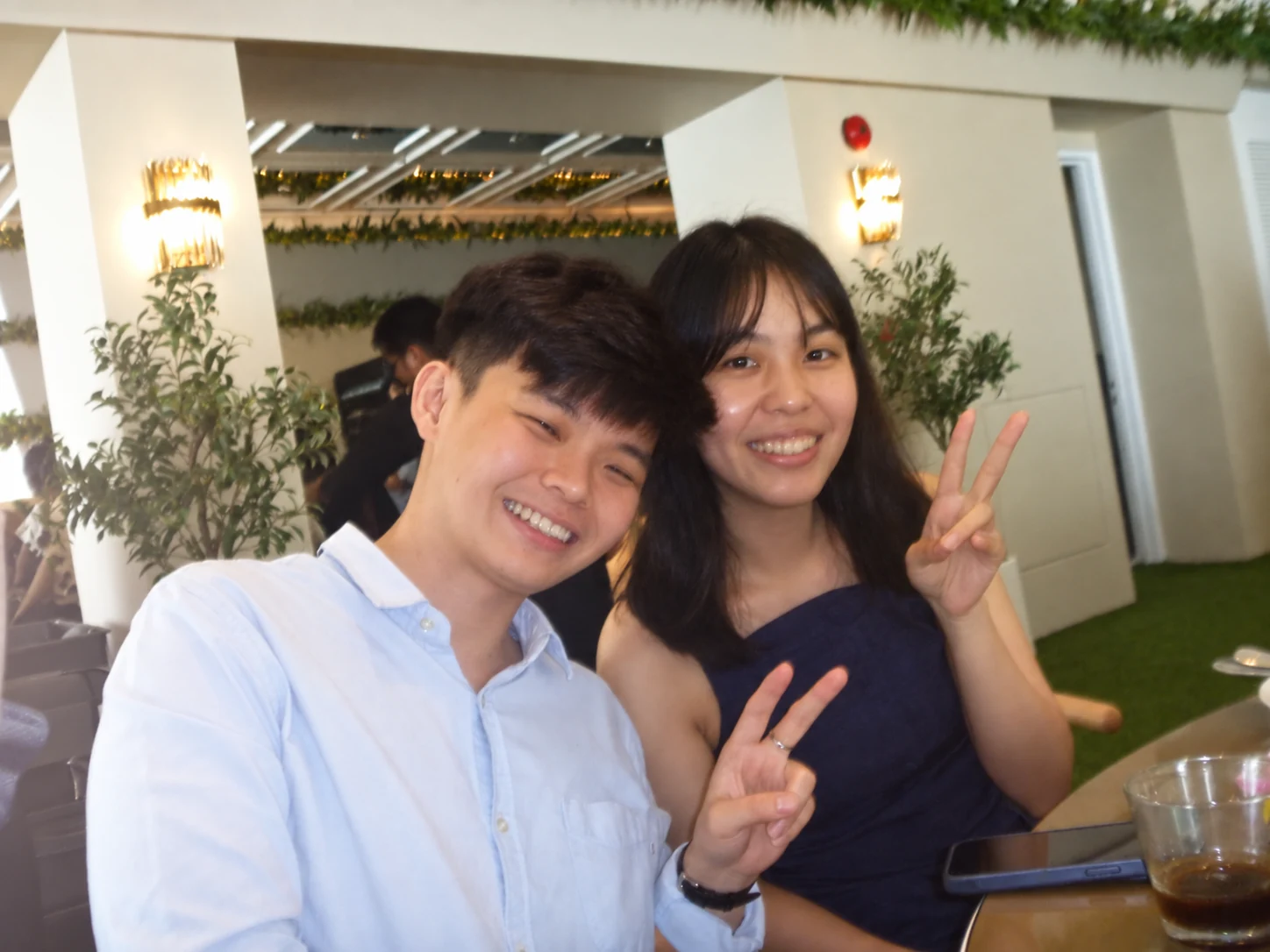 Two friends smiling and making peace signs at a wedding table