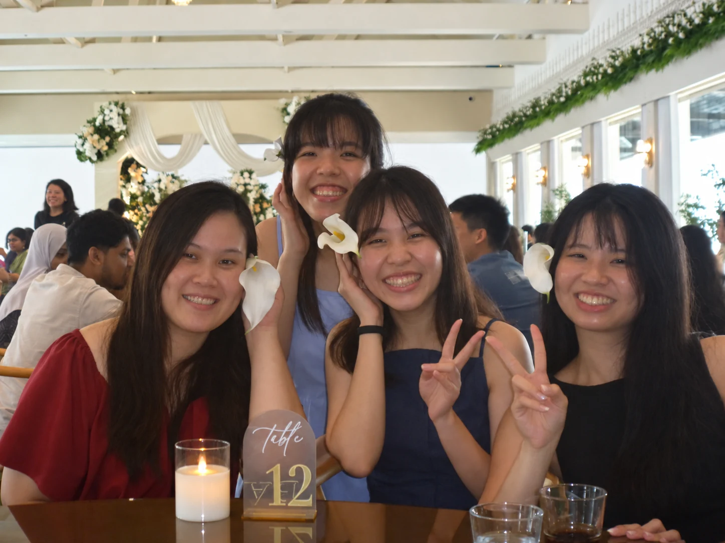 Friends laughing and making peace signs together at table twelve