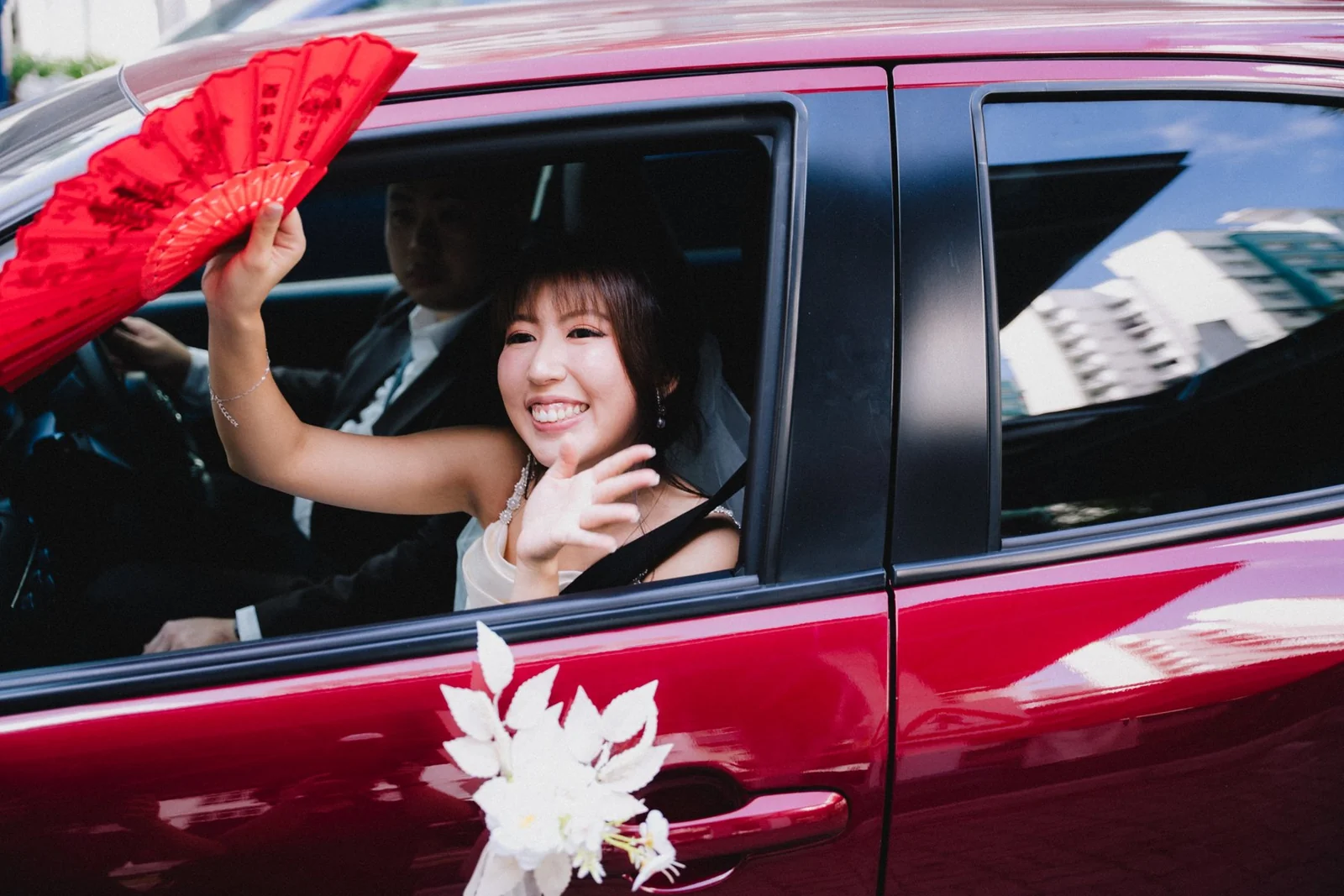 Belle waving from a red wedding car