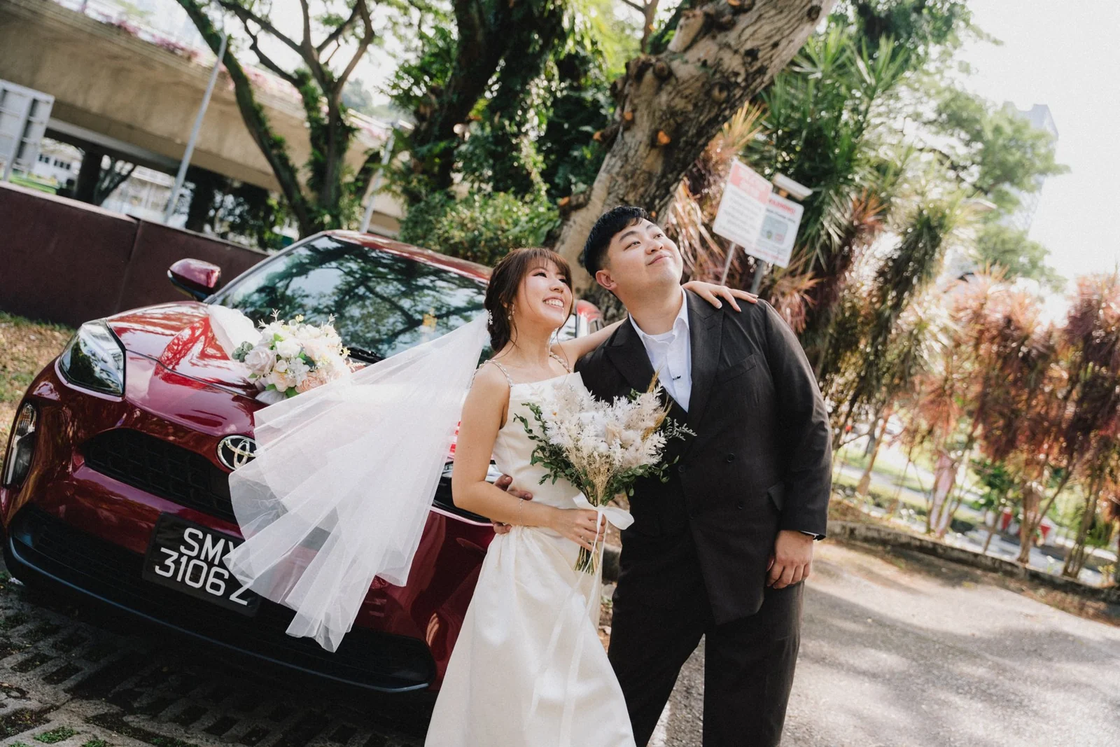 Jason and Belle posing together beside their wedding car