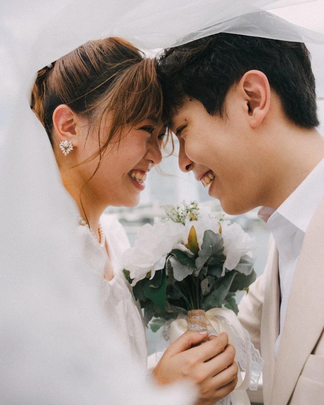 Jerome and Jessica smiling close together beneath a veil